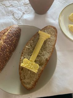 a piece of bread with butter on it sitting next to a baguette that has been cut in half