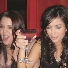 two women sitting next to each other holding wine glasses