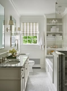 a white bathroom with marble counter tops and cabinets