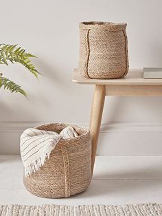 two baskets sitting on top of a rug next to a table with a potted plant