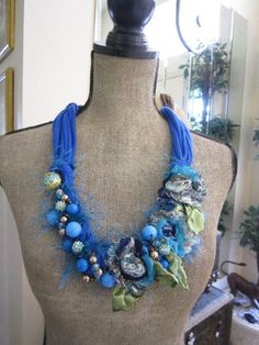 a mannequin wearing a blue necklace with flowers on it's neckline