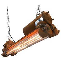 an industrial light fixture hanging from a chain with two lights on it's sides