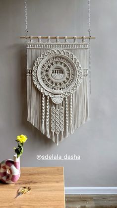 a vase with flowers in it sitting next to a wall hanging