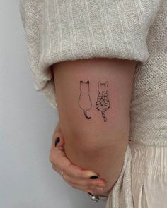 a woman with a small tattoo on her stomach shows the outline of a fox and a cat