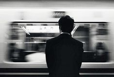 a man standing in front of a train at a subway station with motion blurs behind him