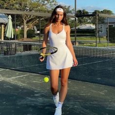 a woman standing on a tennis court with a racquet and ball in her hand