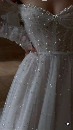 the back of a woman's white dress with pearls on it and text that reads,