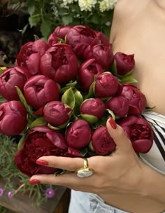 a woman holding a bouquet of red flowers in her left hand and wearing a ring