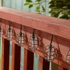 five lights are hanging on the side of a wooden rail