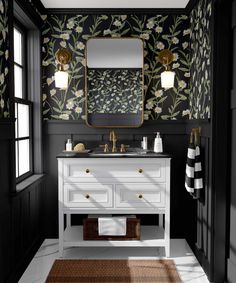 a bathroom with black and white wallpaper, gold accents and a floral pattern on the wall