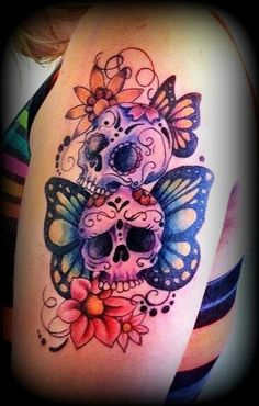 a woman's arm with a skull and butterfly tattoo on it