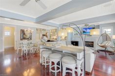 an open concept living room and dining area with wood flooring, white furniture and high ceilings