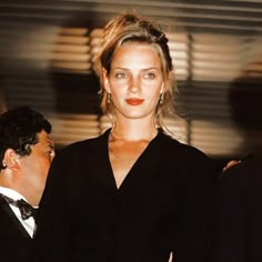 a woman standing next to a man in a tuxedo