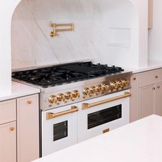 a white and gold kitchen with marble counter tops