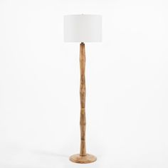 a wooden floor lamp with a white shade on the top and bottom part of it