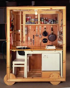 a small kitchen with wooden cabinets and utensils on the wall above it,