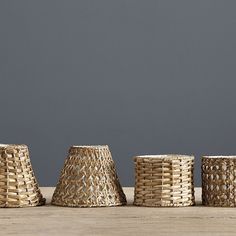 three wicker vases sitting on top of a wooden table next to each other