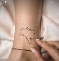 a woman's arm with a small map tattoo on her left wrist and the outline of a heart