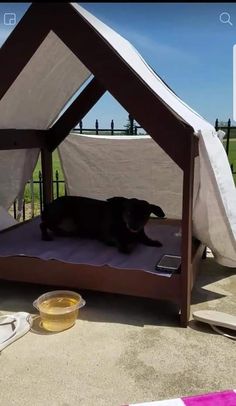 a dog laying on top of a bed under a tent