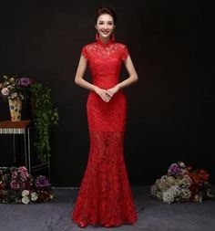 a woman standing in front of a black backdrop wearing a red dress with lace on it