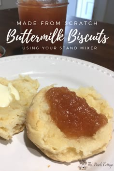 buttermilk biscuits on a white plate with some jam in the background and text overlay reading made from scratch buttermilk biscuits using your stand mixer