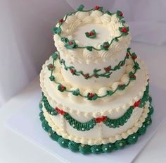 a three tiered cake with holly decorations on it