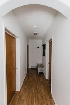 an empty hallway with wooden floors and white walls