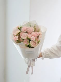 a person holding a bouquet of pink roses