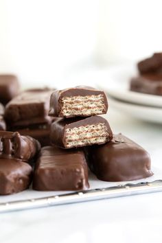 several pieces of chocolate candy stacked on top of each other in front of a white plate