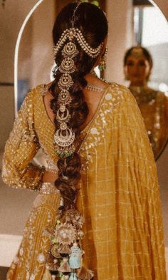 a woman with long hair in a yellow dress looking at her reflection in the mirror