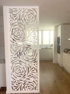 a white room divider sitting on top of a hard wood floor next to a kitchen