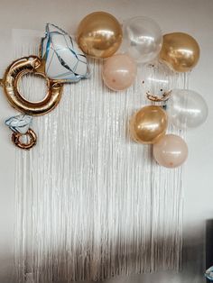 balloons and streamers are hanging on the wall in front of a backdrop with fringes