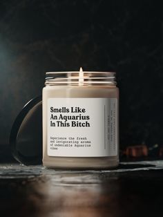 a candle sitting on top of a wooden table next to a black mug with the words smell life in it