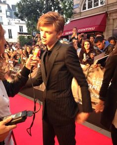 two people standing on a red carpet talking to each other