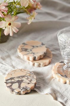 three marble coasters sitting on top of a table next to a vase with flowers