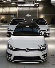 three white volkswagen cars parked in a garage