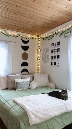 a cat laying on top of a green bed in a room with white sheets and lights