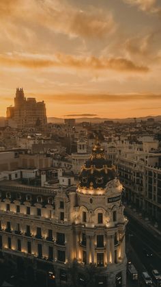 an aerial view of a city at sunset with buildings in the foreground and cars on the street below