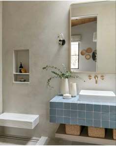 a bathroom with a blue tiled counter top and white sink under a large mirror above it