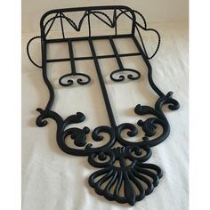 an iron bed frame with ornate designs on the top and bottom, sitting on a white sheet