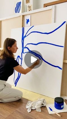 a woman is painting on the wall with blue paint