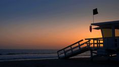 a lifeguard tower on the beach at sunset