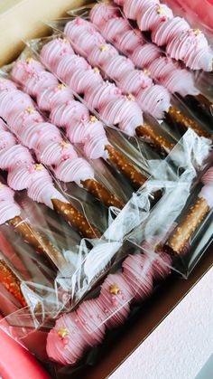 there are many pink and white desserts in the box on this table, all wrapped in plastic