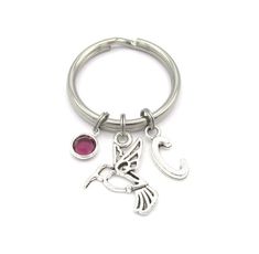 a silver key chain with a bird charm and a red stone in the middle, on a white background