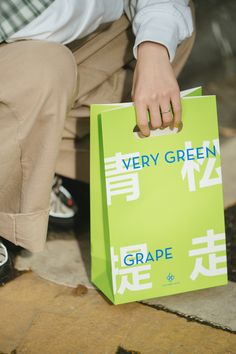 a person holding a green bag with chinese characters on it and the words very green