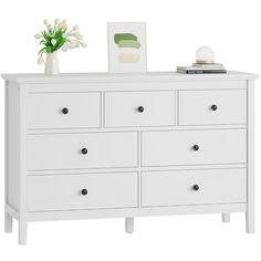 a white dresser with drawers and flowers on top