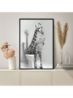 a giraffe sitting on top of a toilet next to a vase filled with flowers