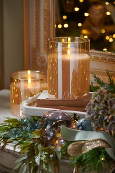 some candles are sitting on a table with christmas decorations