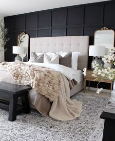 a bedroom with black walls, white bedding and an upholstered headboard