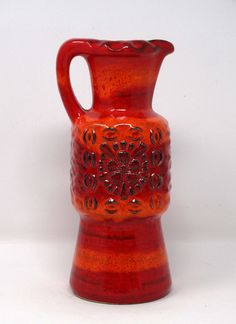 a red glass vase sitting on top of a white table